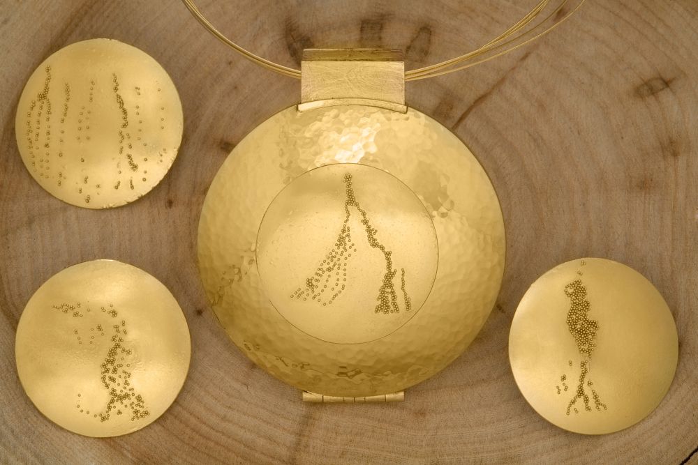 Meisterstück aus 750er Gelbgold mit geschmiedeter Oberfläche und vier auswechselbaren Granulationselementen. Medaillon mit Sprungdeckelmechanik zum Öffnen von Vorder- und Rückseite.